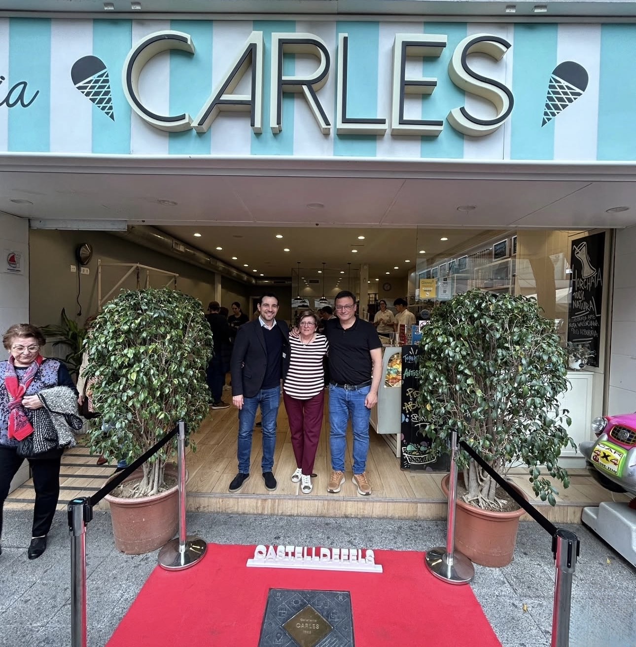 Familia de Gelateria Carles frente al local con la placa emblemática